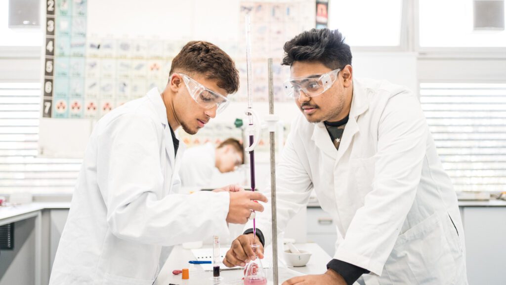 Two male students in lab coats conducting an experiment in the laboratory
